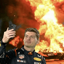 a man taking a selfie in front of a red bull race car