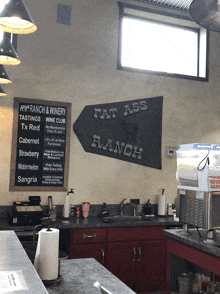 a sign that says fat ass ranch hangs above a kitchen