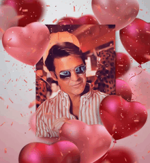 a man wearing sunglasses is surrounded by heart shaped balloons and confetti