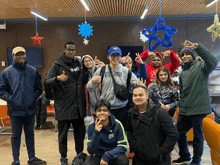 a group of young people are posing for a picture in a room with christmas decorations hanging from the ceiling .