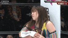 a female wrestler holds a piece of paper that says stardom