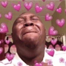 a man is surrounded by pink hearts and flowers and making a funny face .