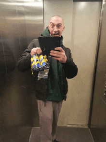 a man is taking a picture of himself in an elevator while holding a pack of diet coke cans