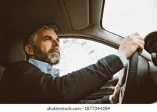 a man with a beard is driving a car .