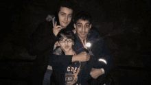 three boys are posing for a picture together in the dark .