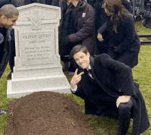 a man kneeling in front of a grave that says oliver queen on it