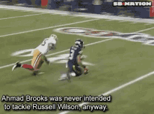 a football player named ahmad brooks is trying to tackle russell wilson on the field