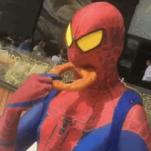 a man in a spider man costume is eating a donut