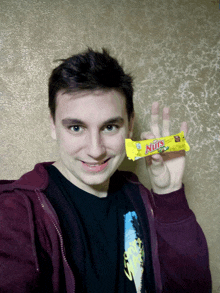 a young man is holding a nuts candy bar in his hand