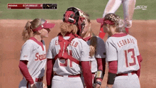 a group of female baseball players are huddled together and one of them has the number 13 on her jersey