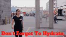 a woman walking in front of an ambulance with the words " do n't forget to hydrate " above her