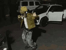 a man is dancing in front of a white car .