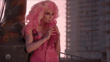 a woman in a pink wig is drinking through a straw from a pink bottle .