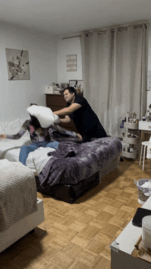 two people are having a pillow fight in a bedroom