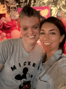 two women posing for a picture with one wearing a mickey shirt