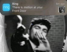a black and white photo of a man covering his mouth with his hand and a ring notification above him