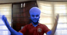 a man with a blue face and a red shirt with the letter s on it is dancing