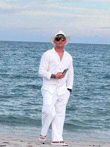 a man in a white shirt and hat is standing on the beach