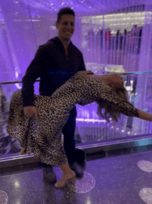 a man is carrying a woman in a leopard print dress on an escalator