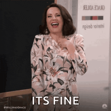 a woman in a floral dress is laughing with the words it 's fine below her