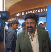 a man in a green suit stands in front of a cafe and concessions sign