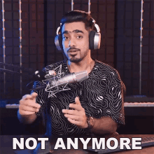 a man wearing headphones is sitting in front of a microphone and says " not anymore "