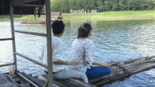 a man and a woman sit on a raft in the water with a sign in the background that says ' thailand ' on it