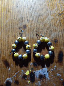 a pair of yellow and silver beaded hoop earrings on a wooden surface