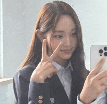 a girl in a suit is taking a selfie with her phone