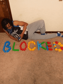 a man laying on the floor with the word blocked made out of lego