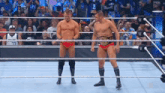 two wrestlers are standing in a wrestling ring with a crowd in the background .