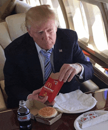 a man in a suit and tie is eating a mcdonald 's lunchtime sandwich