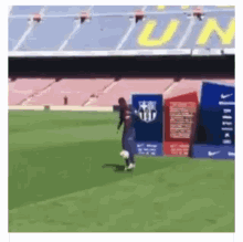 a man is kicking a soccer ball on a field in front of an empty stadium with the word un on it