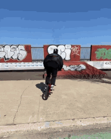 a person is riding a bike in front of a wall that has graffiti on it including the letters bt