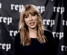 a woman with blonde hair and bangs is standing in front of a black curtain with the word rep on it .