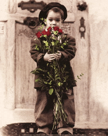 a young boy is holding a bouquet of flowers in front of a door