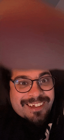 a man with glasses and a mustache is smiling for the camera