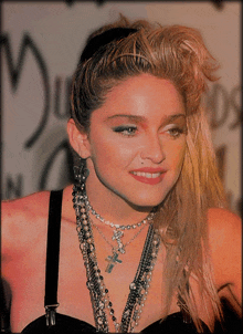 a woman wearing a black top and a necklace with a cross on it