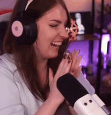 a woman wearing headphones is laughing while sitting in front of a microphone