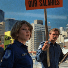 a man and a woman are holding up a sign that says our salaries