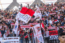 a crowd of people in a stadium holding flags and a sign that says biji amed spor zaxo bite re ye