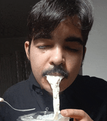 a man with a mustache is eating something with a spoon in his mouth