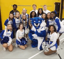 a group of cheerleaders and a blue mascot are posing for a picture .