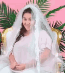 a woman in a wedding dress and veil is sitting on a chair .