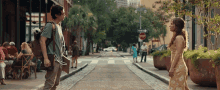 a man and a woman are standing on the side of a street with a stop sign in the background