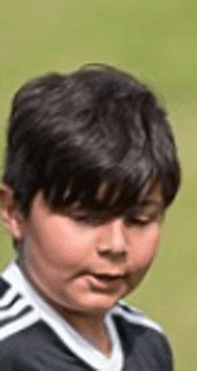 a young boy wearing a black and white soccer jersey is making a face .