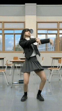 a girl in a suit and skirt is dancing in a classroom