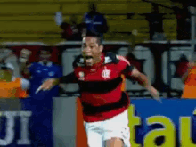 a man in a red and black striped shirt is running on a soccer field in front of a sign that says ui