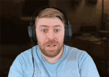 a man wearing headphones and a blue shirt looks surprised