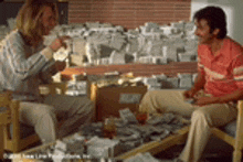 two men are sitting at a table with newspapers on it